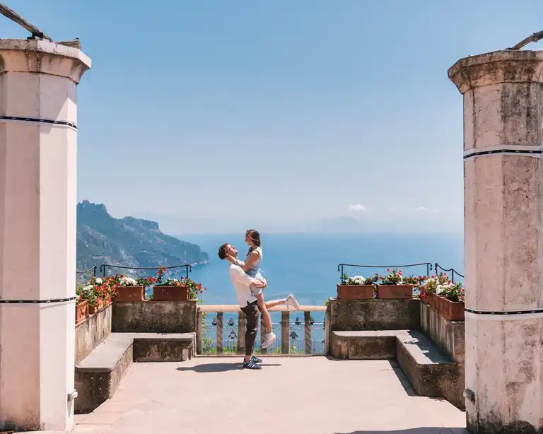 Boyfriend lifting up her girlfriend on the main balcony of Villa Rufolo overlooking Amalfi Coast