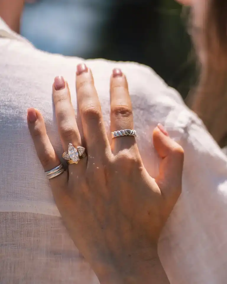 Close up of engagement ring with peculiar design as she hugs her boyfriend shoulder