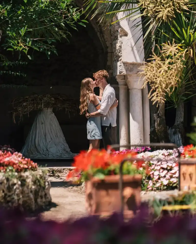 Two lovers kissing in the gardens of Villa Rufolo in Ravello surrounded by flowers and antique architecture