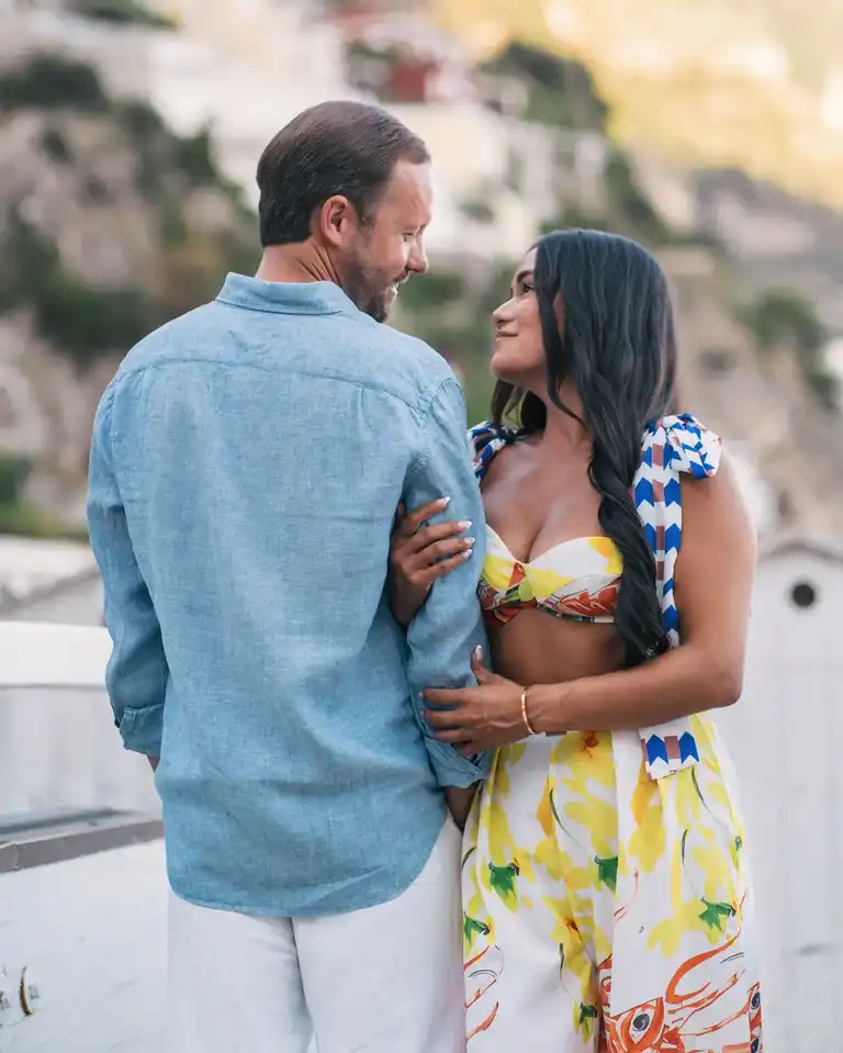 A woman hugging her fiancé arm looking at each other in Positano