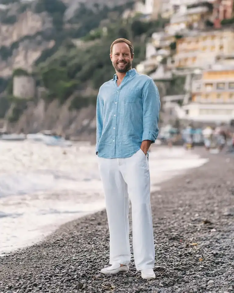 A man wearing azure linen shirt and white linen pants in Positano by Spiaggia Grande