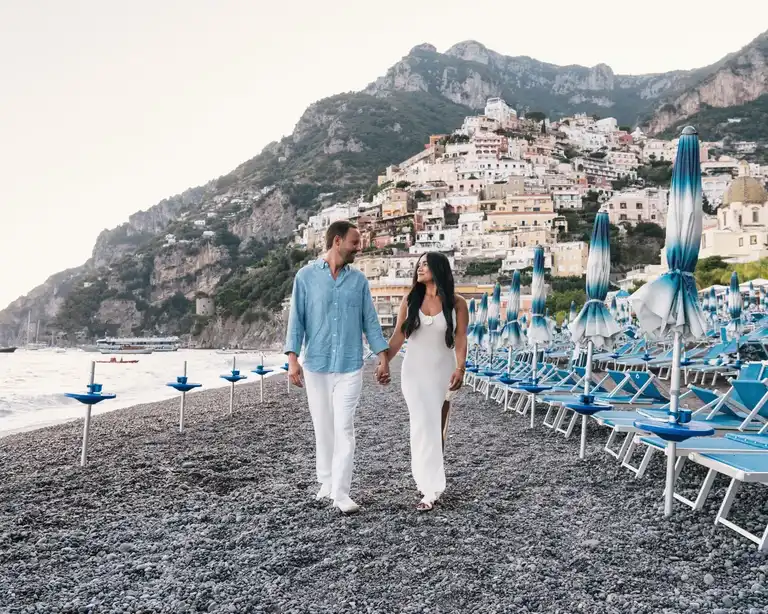Couple walking through the surf of Spiaggia Grande in Positano dressed formally