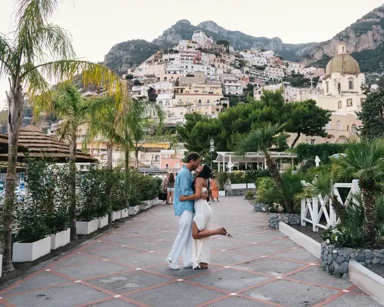 Couple kissing in Positano with a view of the colored houses in the background