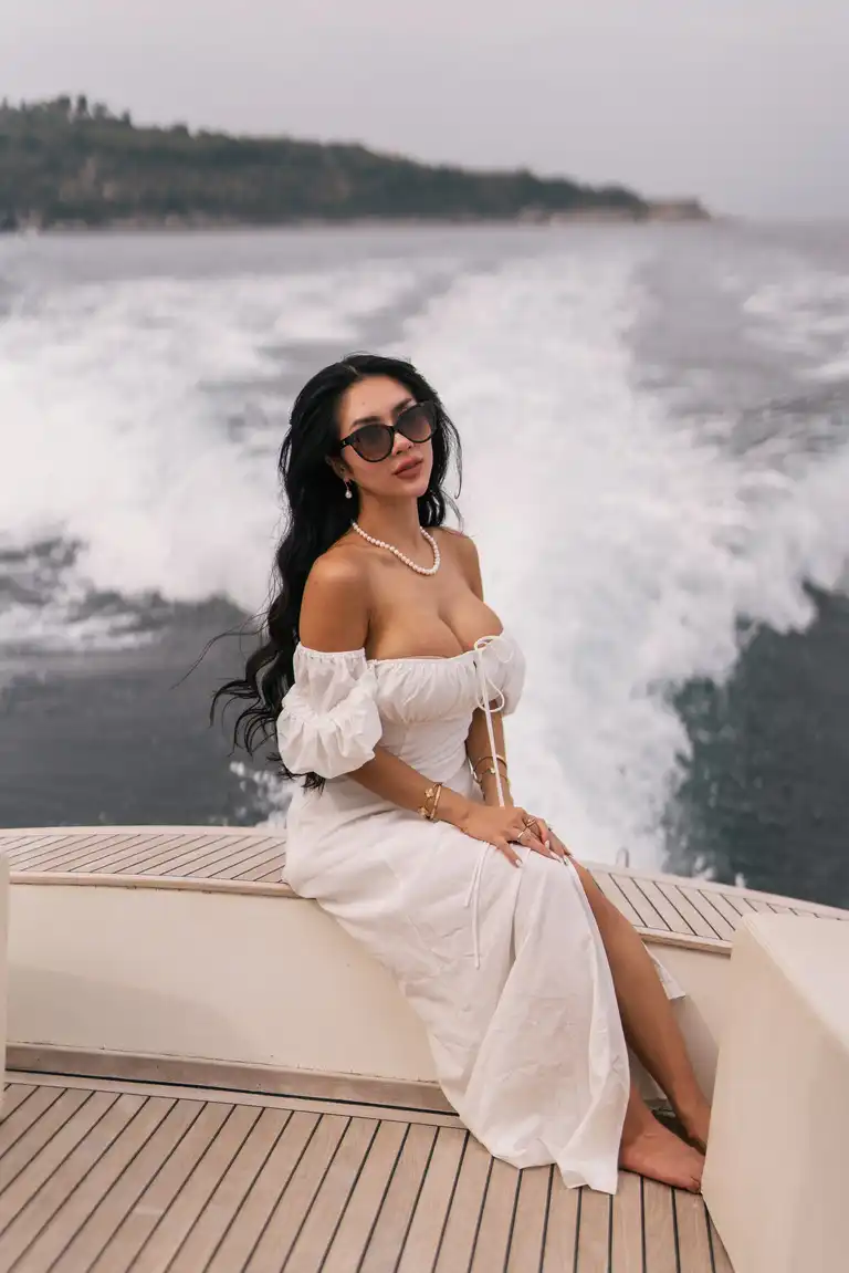 Woman wearing white dress and sunglasses on a boat in Sorrento