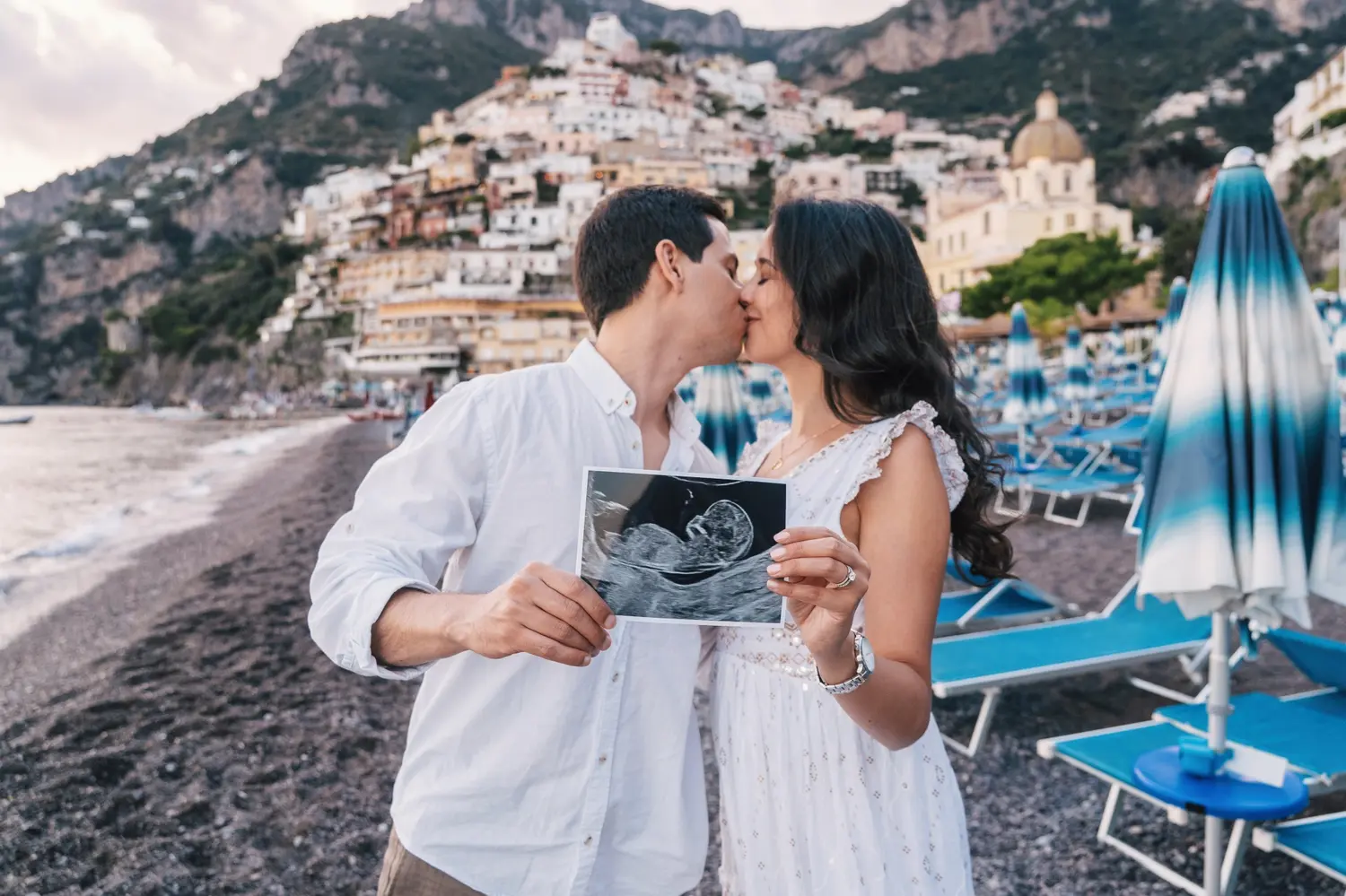 Couple holding ultrasound picture of their baby between hand for maternity photoshoot in Positano