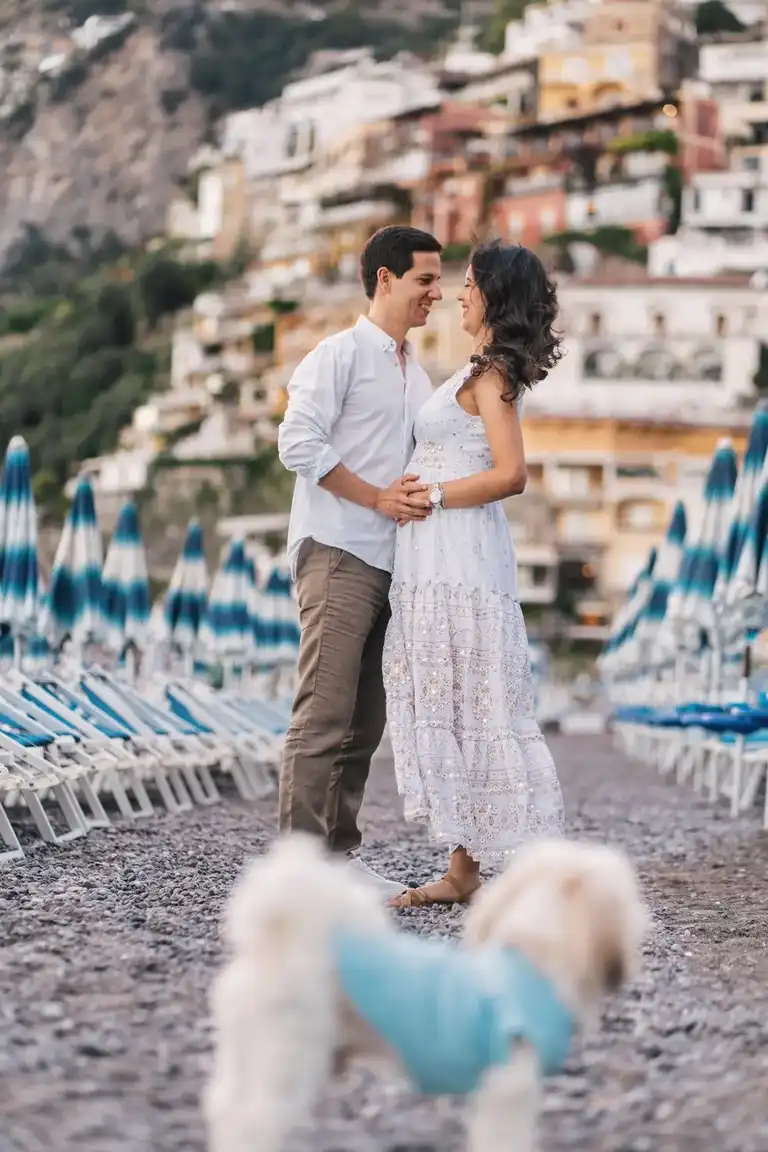 A couple kissing in the background while their dog pet looks at them in foreground in Positano on the beach