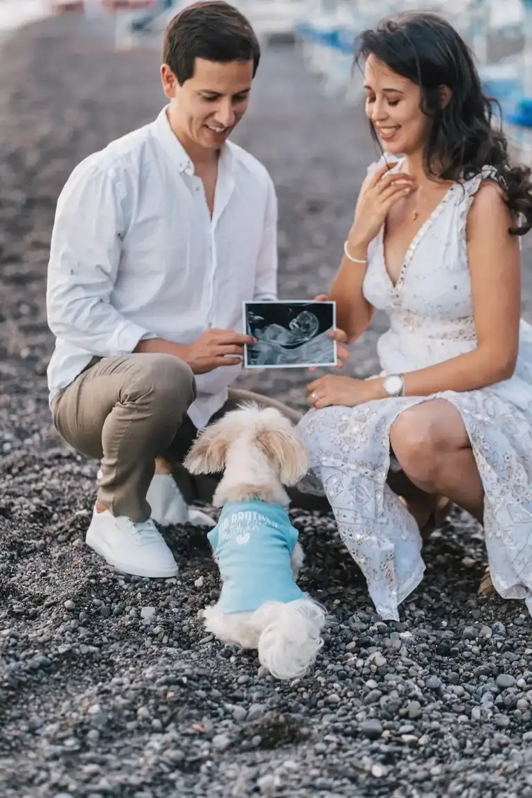 Couple squatting showing their dog the ultrasound picture of the baby coming 