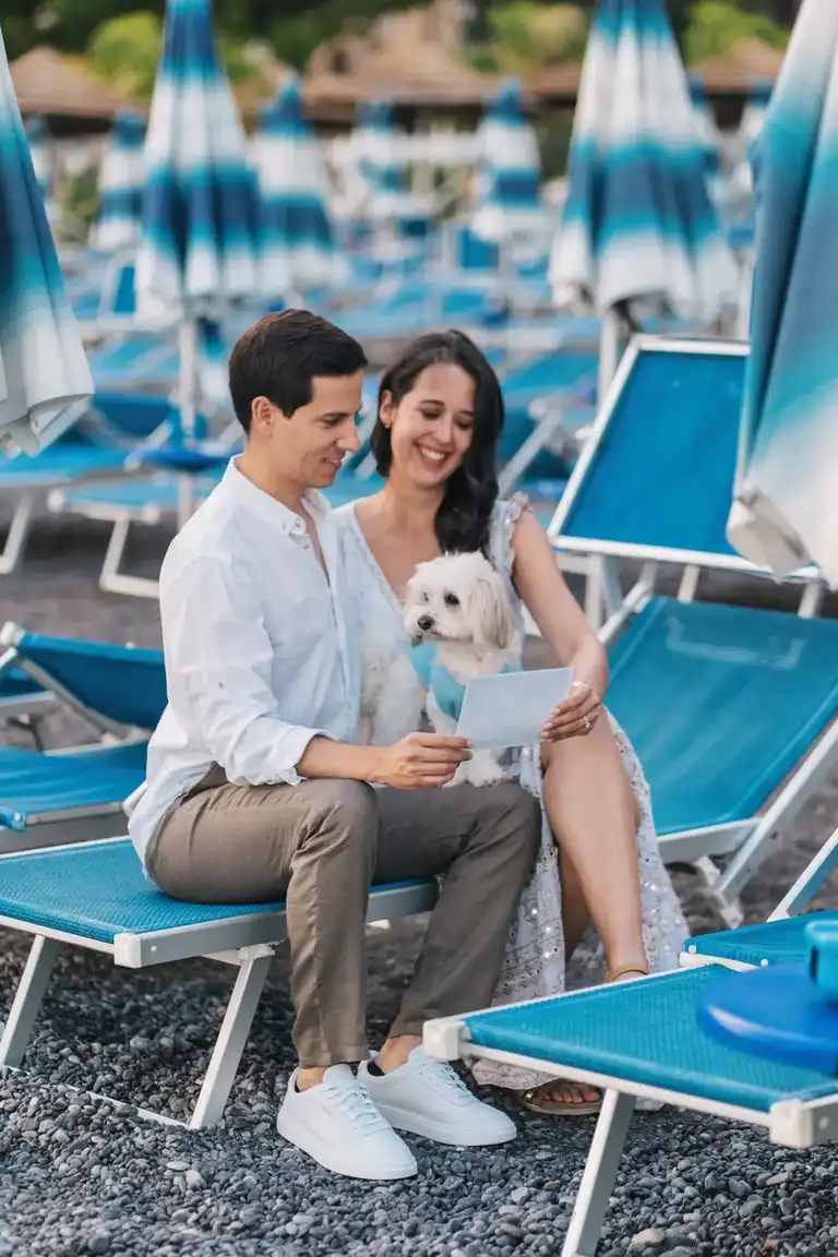 Couple sitting together by Spiaggia Grande in Positano on a lounge chair playing with their dog