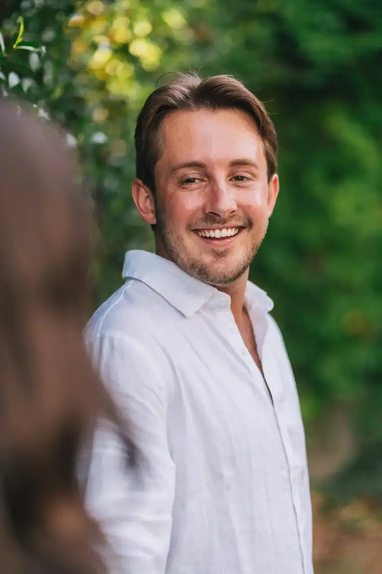 Smiling man in focus looking at his girlfriend out of focus after he proposed in Sorrento