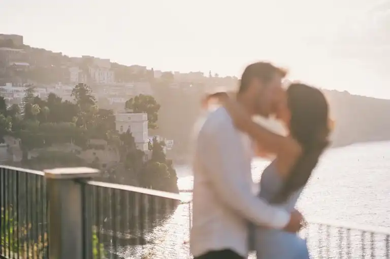 Couple out of focus kissing with Sorrento view in the background 