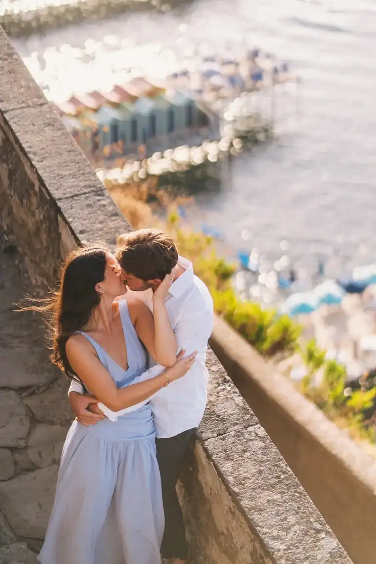 A couple cuddling and kissing while leeaning against the wall of the stairs from Villa Comunale in Sorrento down to the beach and Marina Piccola