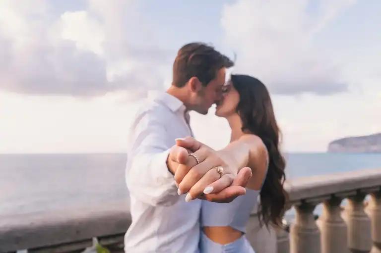 couple holding hands together showcasing engagement ring on a balcony with seaview in Sorrento