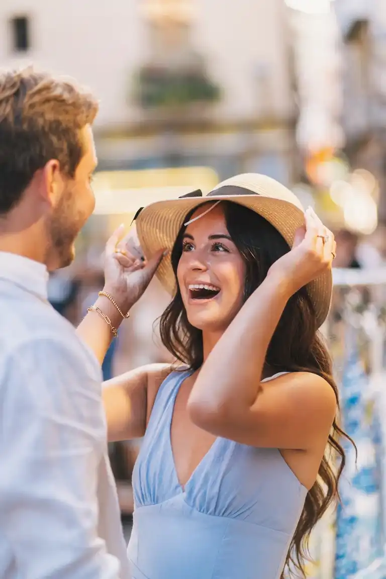 Couple sharing fun moments shopping by the alleways of Sorrento as she tries a handmade straw hat