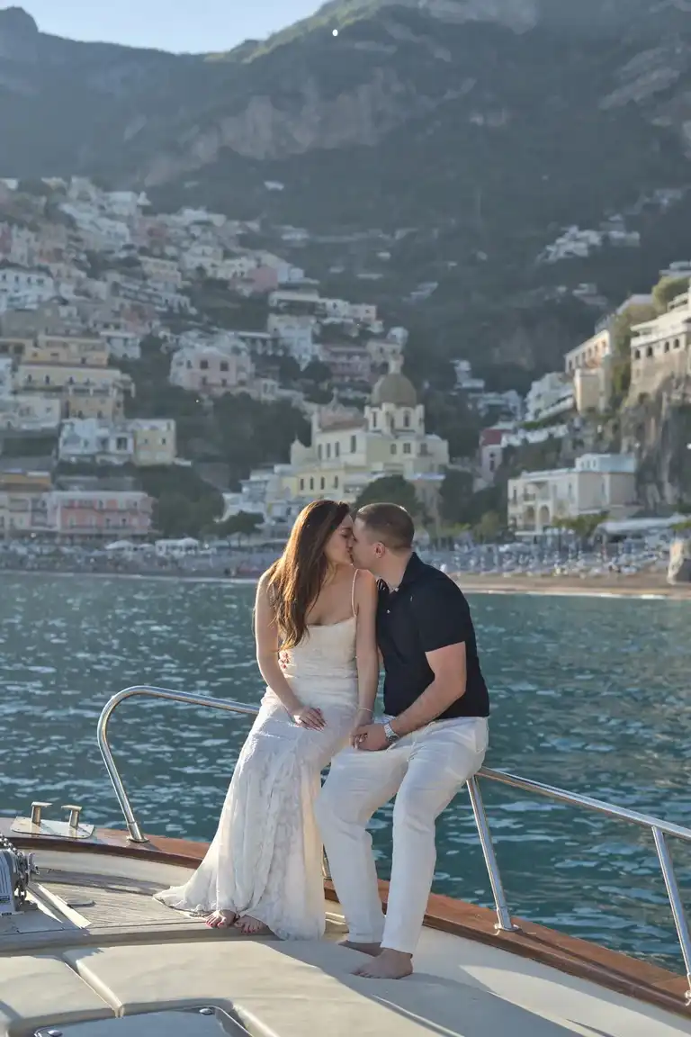 Couple sharing an intimate moment sitting in a boat with Positano in the background