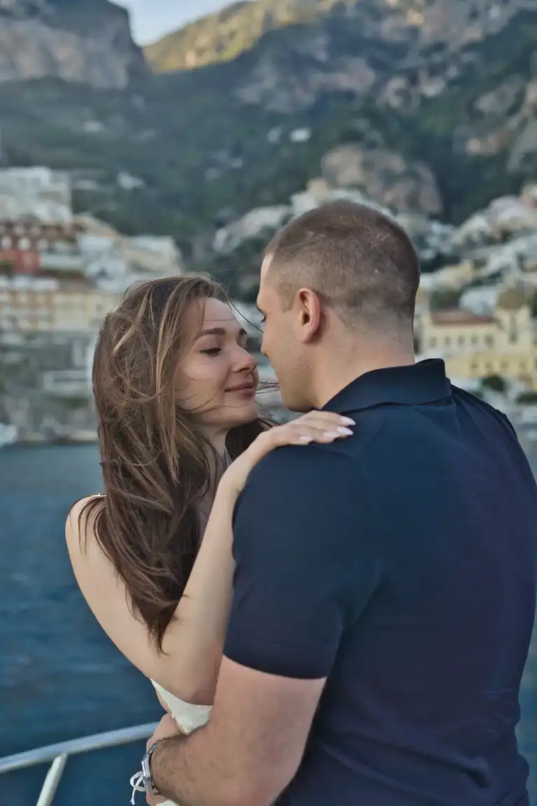 Couple romantically holding each other on a boat with Positano in the back