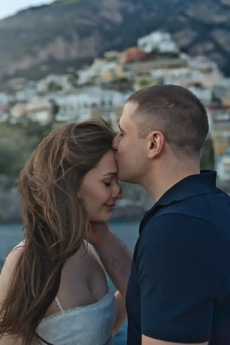 Man kissing her girlfriend's forehead during a photoshoot in front of Positano