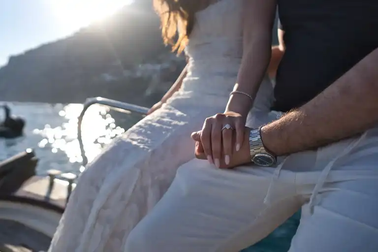 Couple holding each other's hands with proposal ring on display, on a boat 