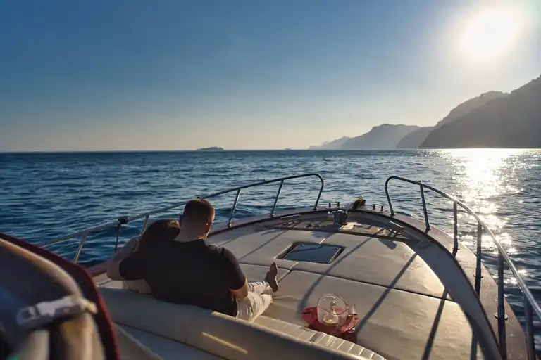 Couple looking at sunset outside Praiano while relaxing on a rental boat