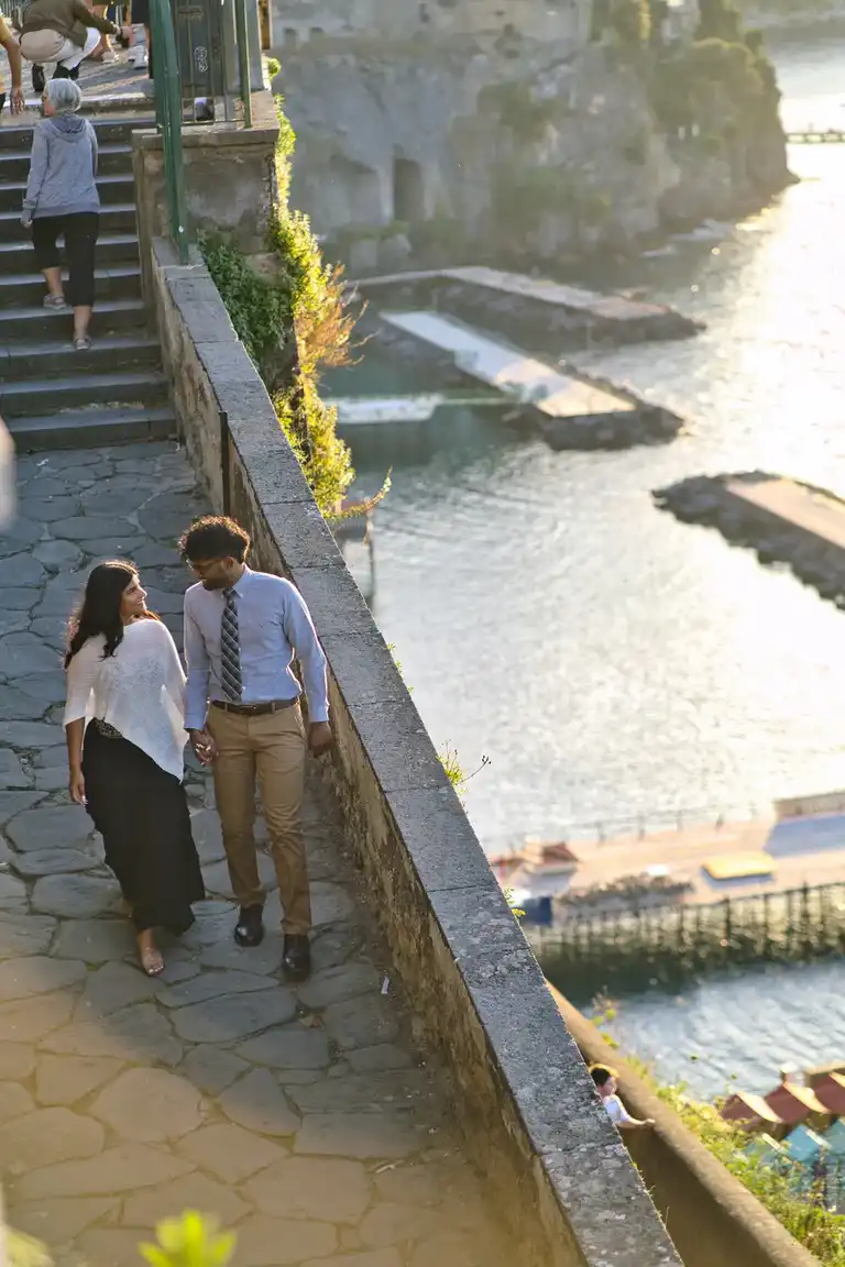 Couple walking down the steps of Villa Comunale with the beach of Sorrento in the backdrop