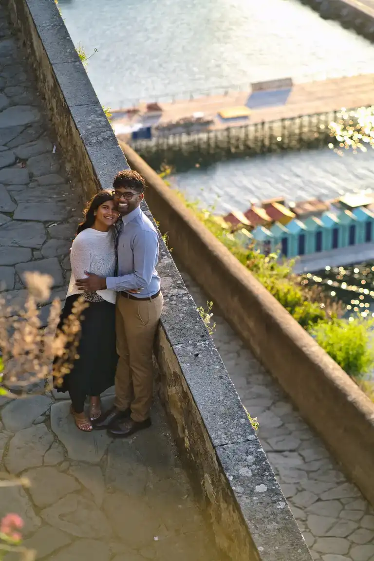 Couple smiling at the camera down the steps of Villa Comunale with the beach of Sorrento in the backdrop