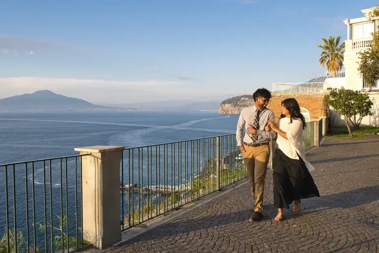 Couple walking in Villa Comunale of Sorrento holding hands by the balcony