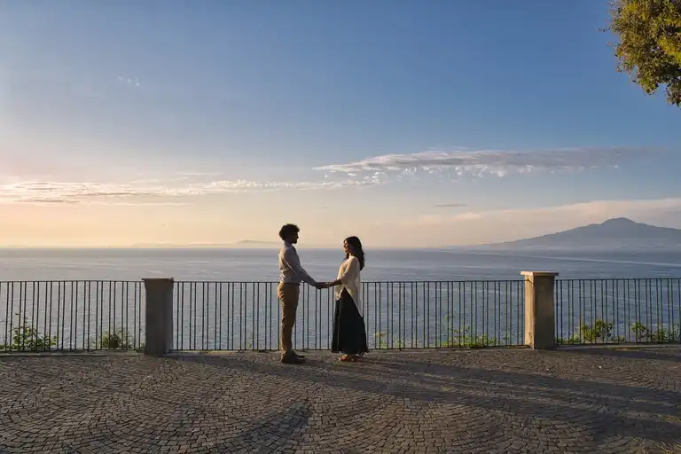 Couple facing each other holding hands on the balcony of Villa Comunale