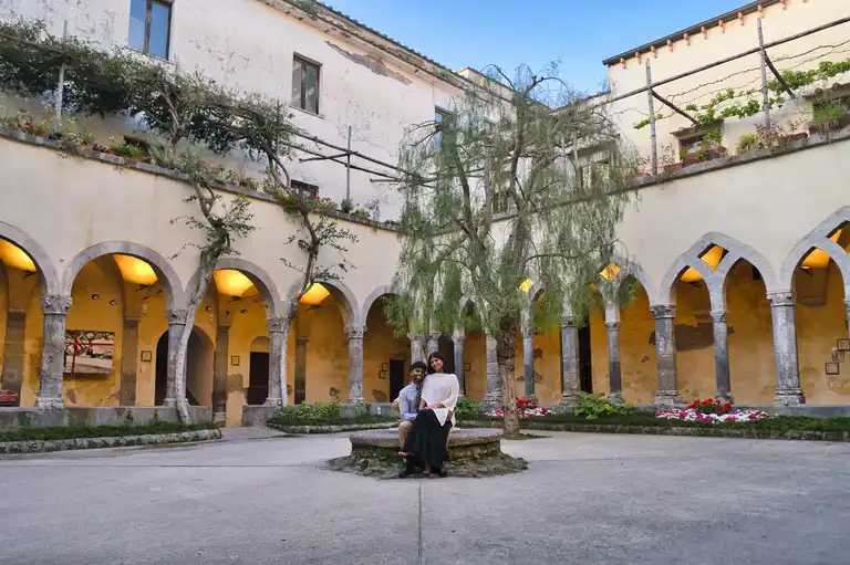 Couple sitting on the well of cloister of San Francesco in Sorrento