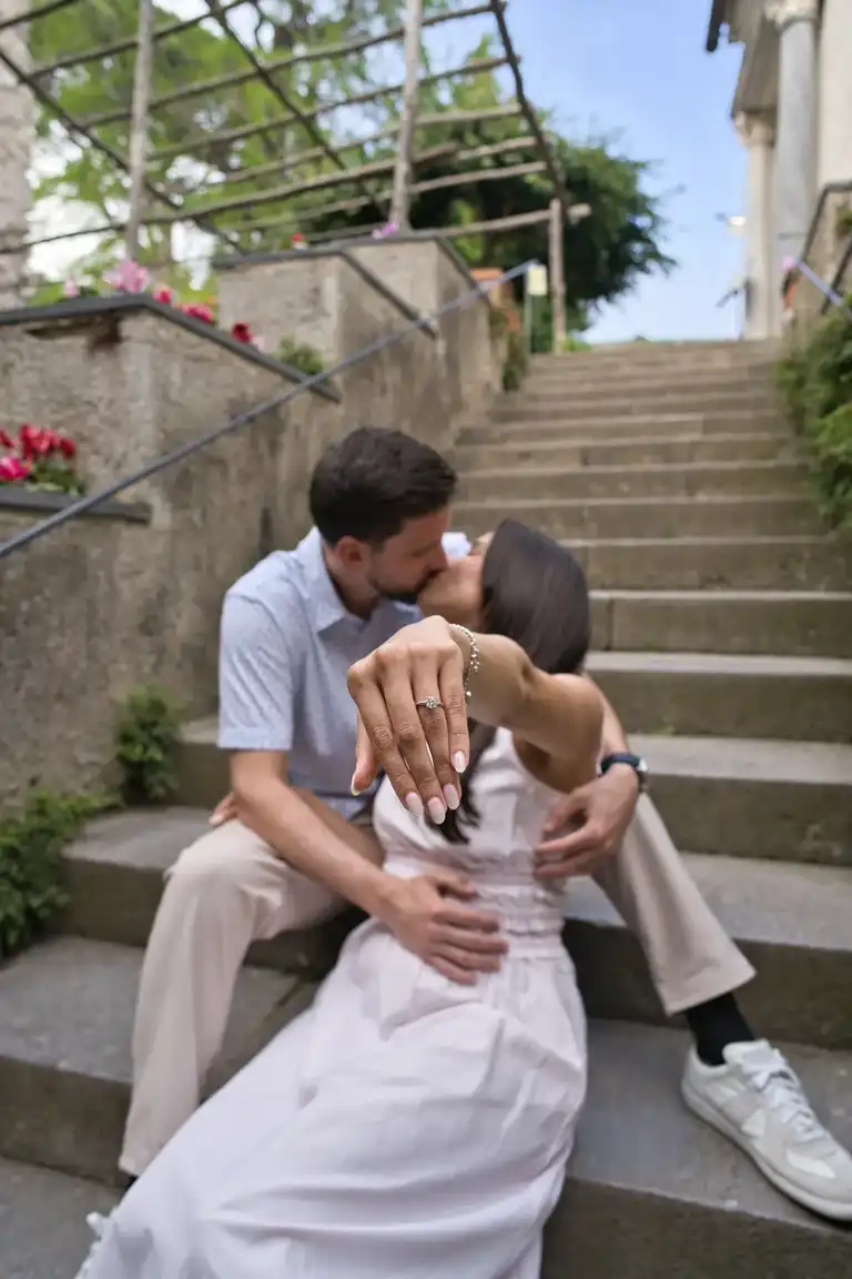 Couple showing proudly the ring while kissing sitting on the stairs leading up to the tower of Villa Rufolo in Ravello