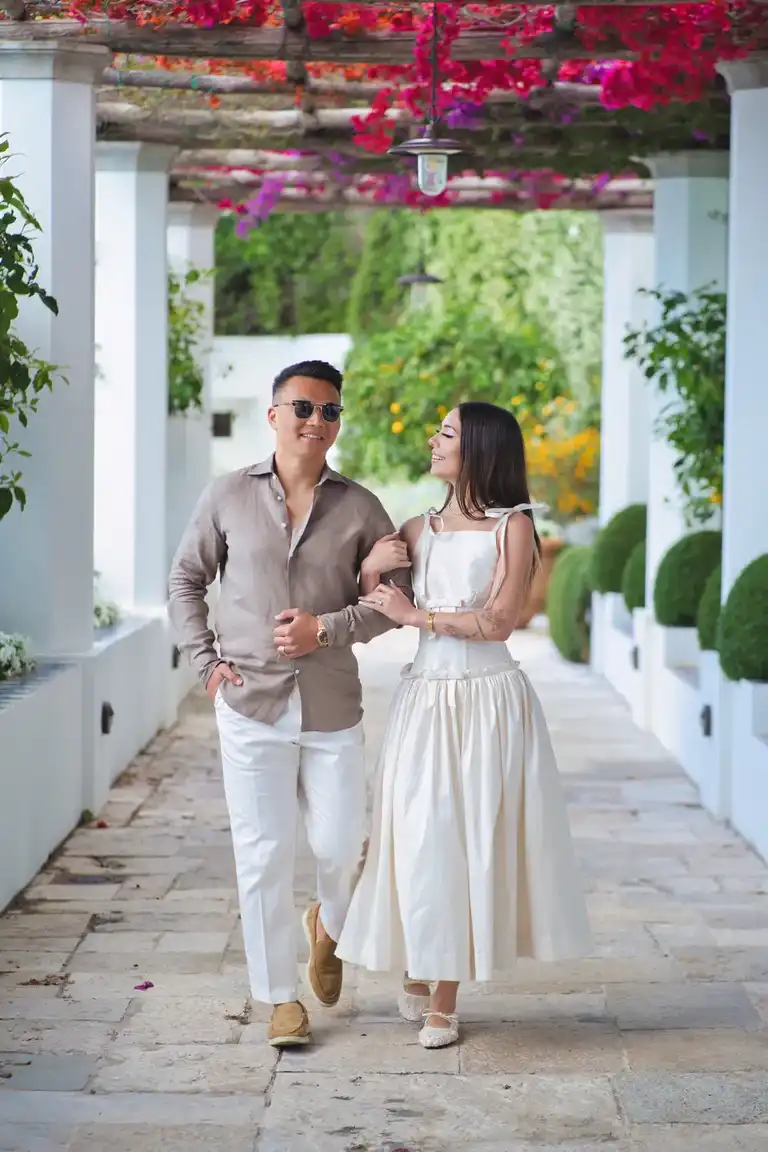 The newlyweds hold hands and lean close together on a terrace overlooking the small bay and buildings of Conca dei Marini beneath Borgo Sant'Andrea.
