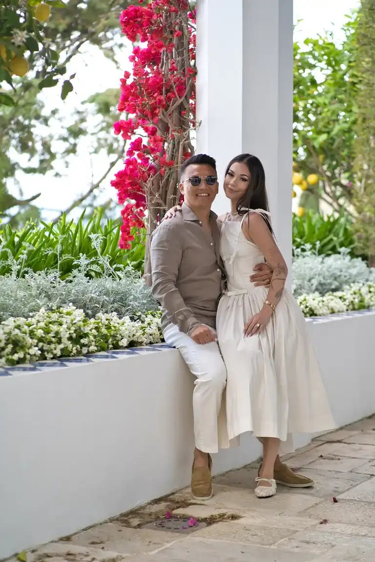 The bride and groom pose in a modern, light-filled patio area within Borgo Sant'Andrea, featuring arched whitewashed walls and a distinctive geometric blue and white tiled floor.