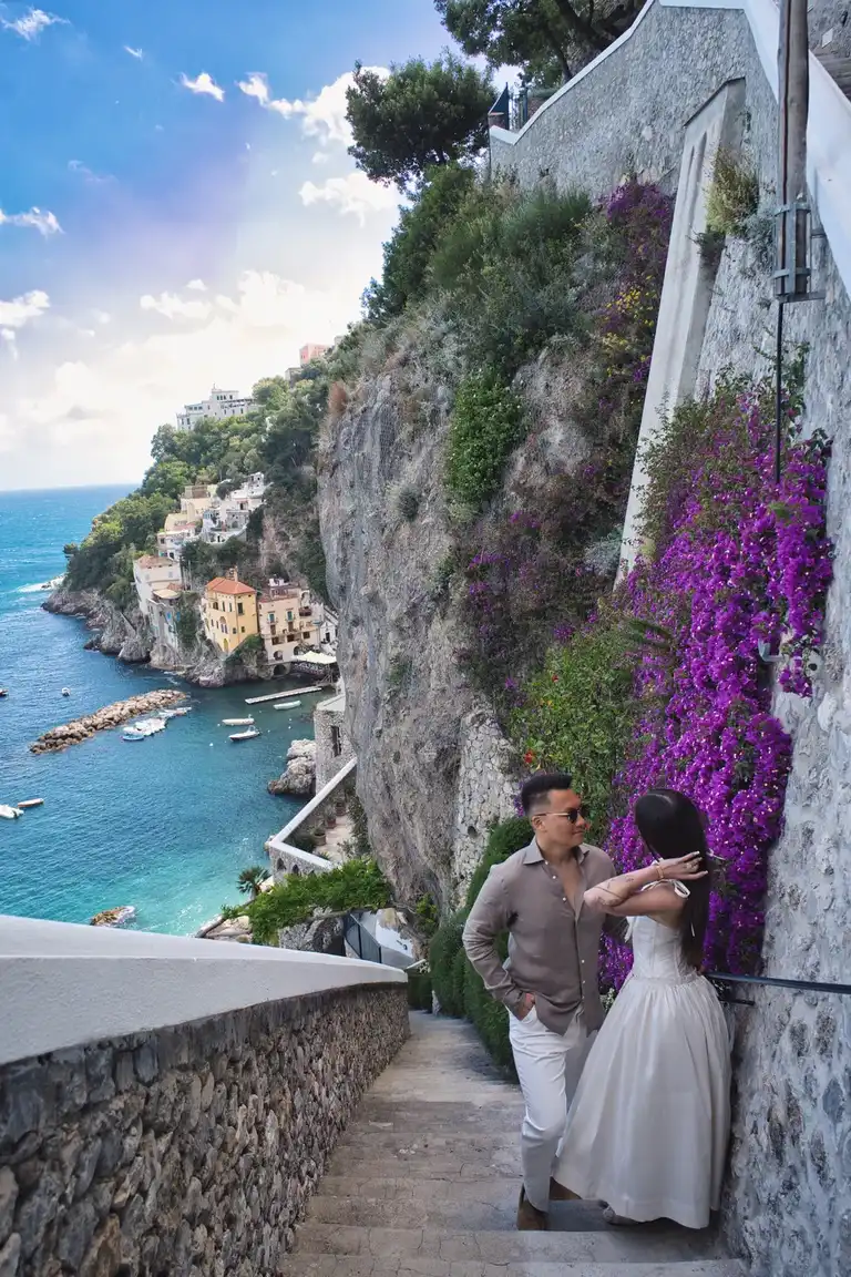 A close-up detail shot of the newlyweds resting on a rustic stone railing overlooking the blue Mediterranean sea at Borgo Sant'Andrea.