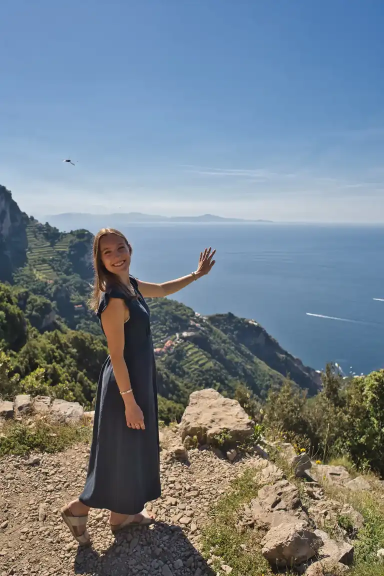 Casual portrait of an engaged girl showing off the proposal ring standing on the Path of the Gods trail above the Amalfi Coast during sunrise.