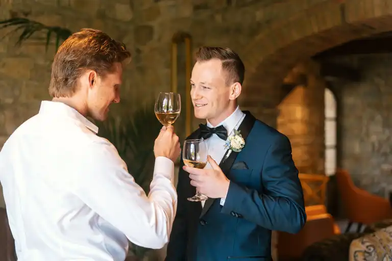 Broom posing with his best friend as they share a drink before the wedding ceremony