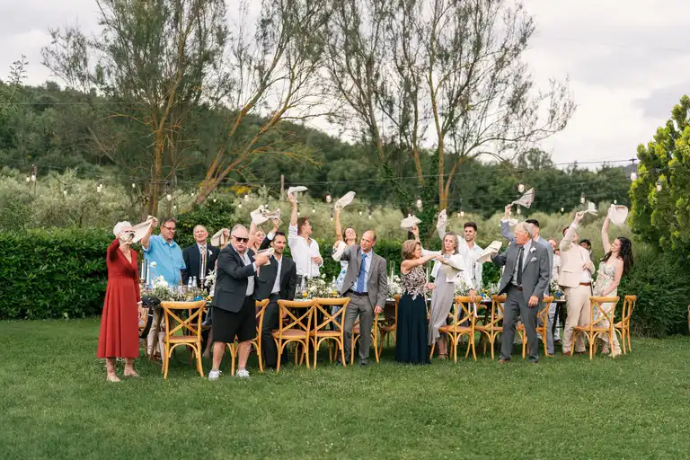Wedding guests standing at the table in Tuscany Villa being joyous as they dance with their white napking in a typical italian folktale song