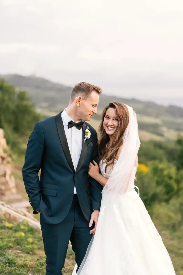 Broom and Bride with her veil pose for pictures between Tuscany hills