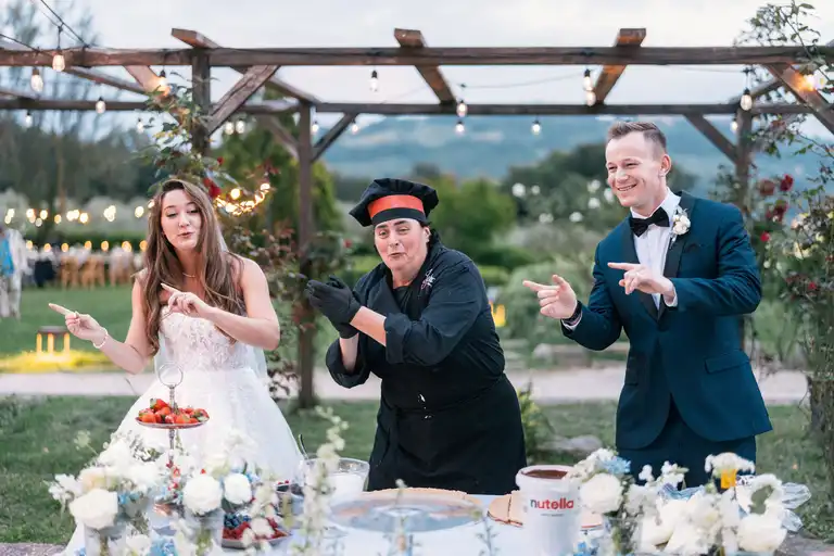 Bride and broom prepare a typical italian cake together with chef during their tuscany wedding