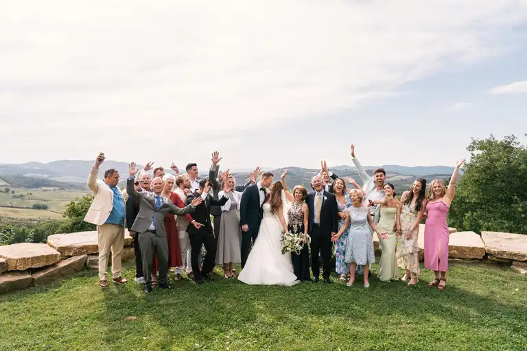 group photo of bride, broom and guests between the hills of Tuscany